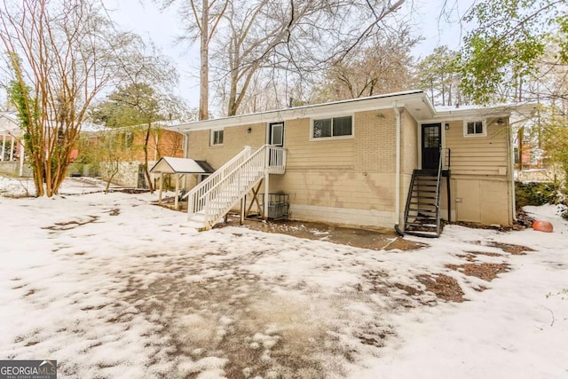 snow covered house featuring cooling unit