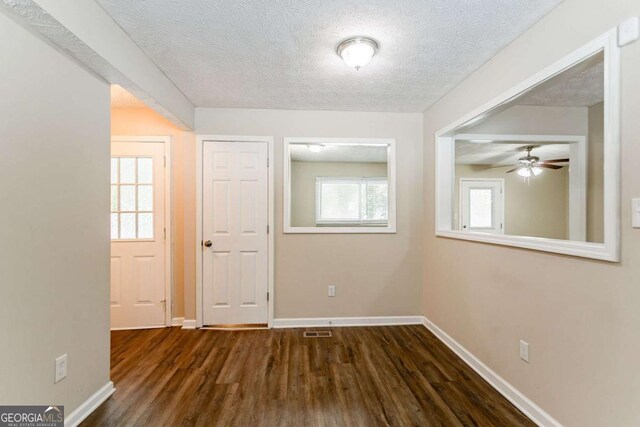 unfurnished room with a textured ceiling and dark hardwood / wood-style floors