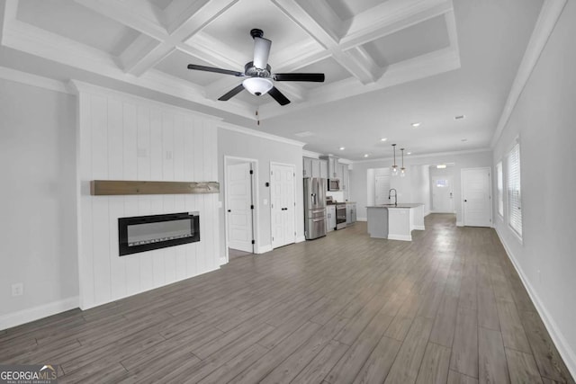 unfurnished living room featuring a fireplace, coffered ceiling, dark wood-type flooring, and ornamental molding