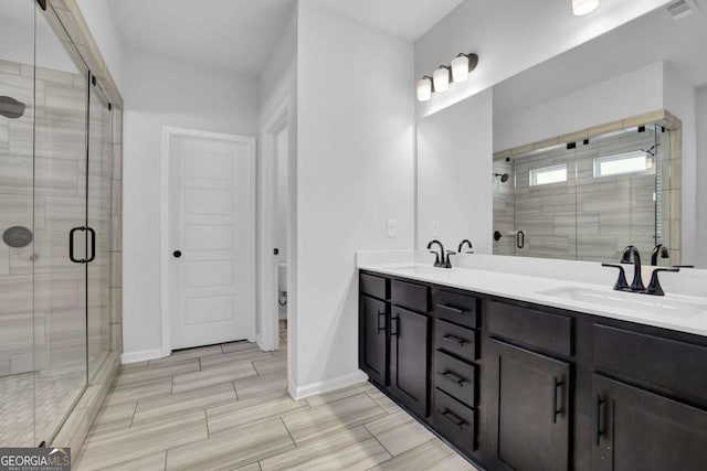 bathroom with a shower with door, toilet, and vanity