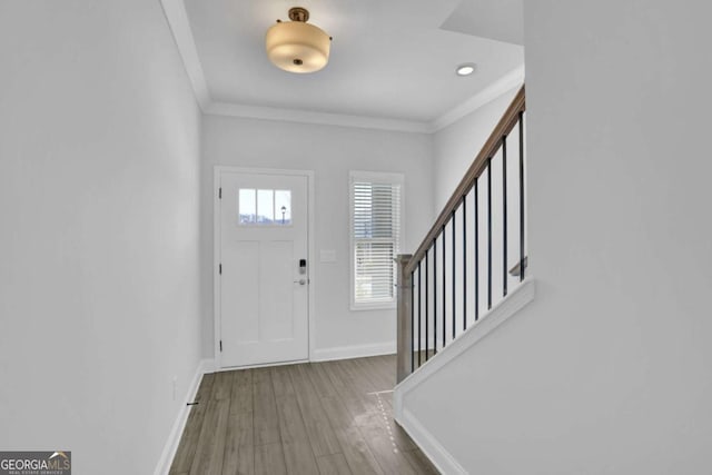 entryway with hardwood / wood-style flooring and crown molding