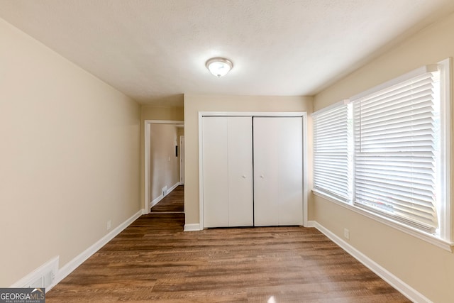 unfurnished bedroom featuring a closet, wood-type flooring, and multiple windows