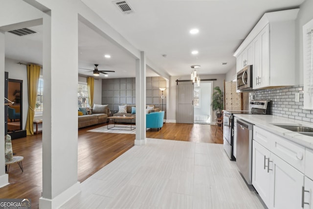 kitchen featuring light stone countertops, white cabinets, stainless steel appliances, a healthy amount of sunlight, and tasteful backsplash