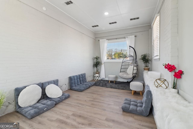 living area with light hardwood / wood-style floors and brick wall