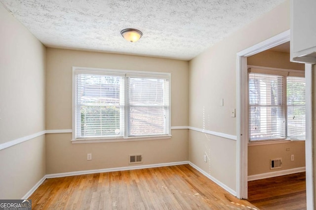 spare room with light hardwood / wood-style floors and a textured ceiling