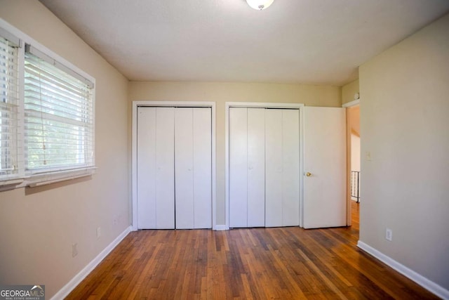 unfurnished bedroom featuring multiple closets and dark hardwood / wood-style floors