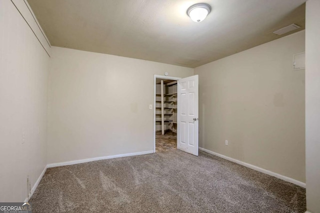 unfurnished bedroom with a closet, carpet flooring, and a spacious closet