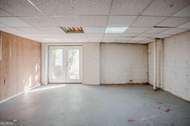 spare room featuring french doors, concrete floors, and a drop ceiling