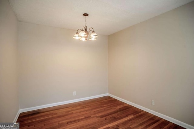 empty room with an inviting chandelier and dark wood-type flooring