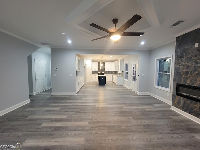 unfurnished living room featuring dark wood-type flooring, ornamental molding, a tile fireplace, and ceiling fan