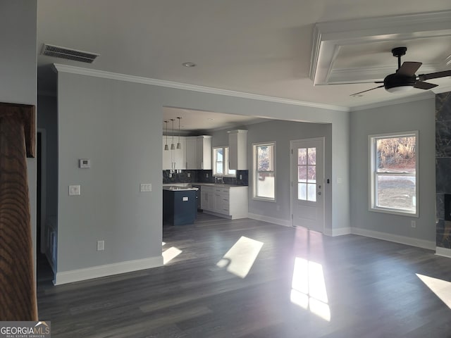 unfurnished living room with crown molding, plenty of natural light, and dark hardwood / wood-style flooring