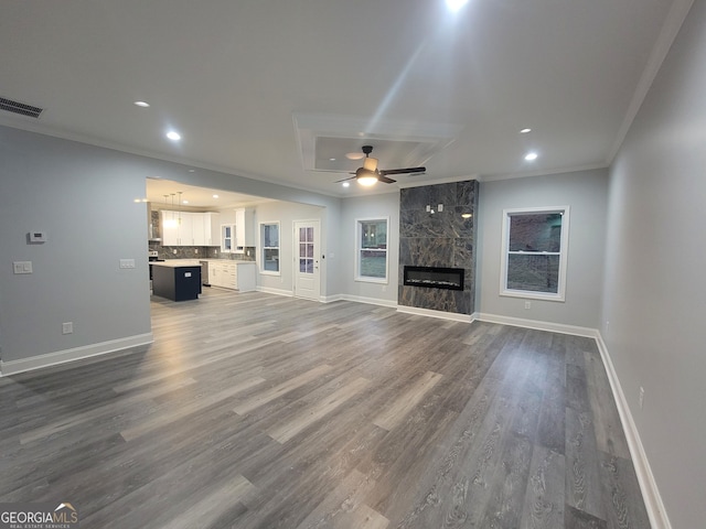 unfurnished living room with dark wood-type flooring, ornamental molding, and a premium fireplace