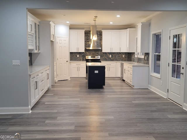 kitchen with wall chimney range hood, dark wood-type flooring, hanging light fixtures, and white cabinets