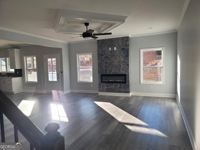 unfurnished living room with a wealth of natural light, a fireplace, a raised ceiling, crown molding, and dark wood-type flooring