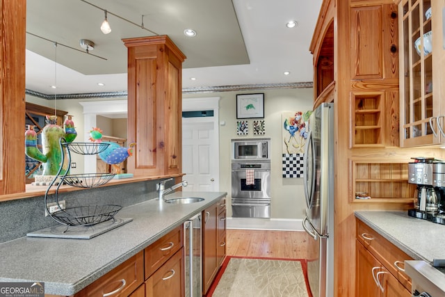 kitchen featuring appliances with stainless steel finishes, sink, beverage cooler, and light hardwood / wood-style floors