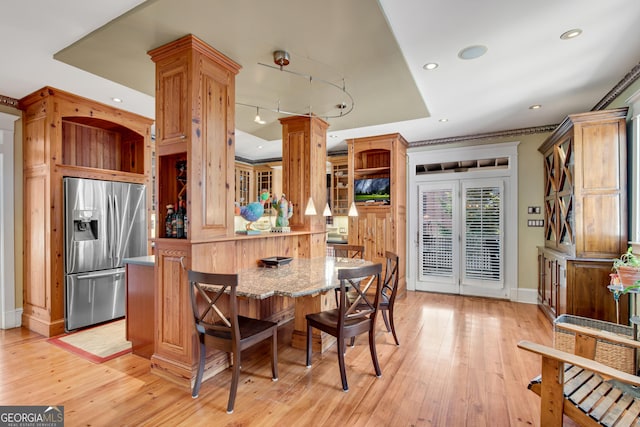 kitchen with stainless steel fridge with ice dispenser, light hardwood / wood-style flooring, kitchen peninsula, and a kitchen bar