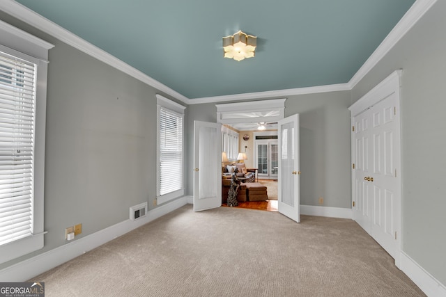 unfurnished bedroom featuring multiple windows, crown molding, and light colored carpet