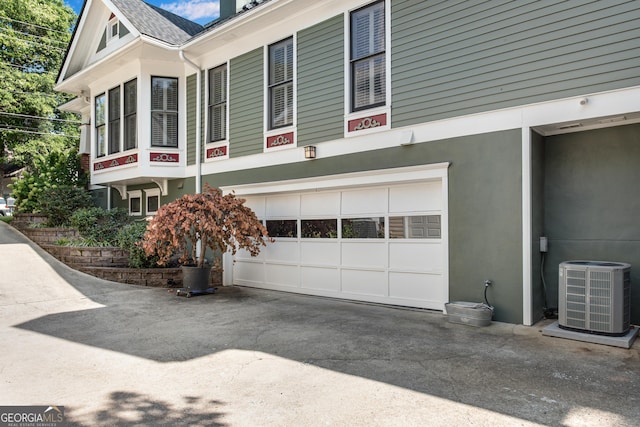 view of side of home with a garage and central AC