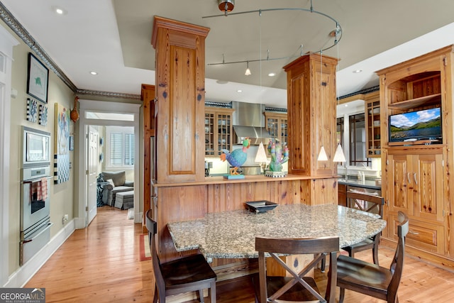 kitchen with light hardwood / wood-style floors, stainless steel appliances, kitchen peninsula, and ornate columns