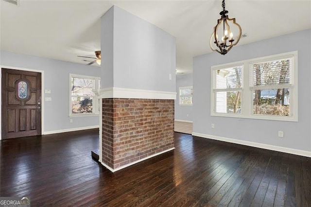 foyer featuring ceiling fan with notable chandelier, a brick fireplace, and dark wood-type flooring