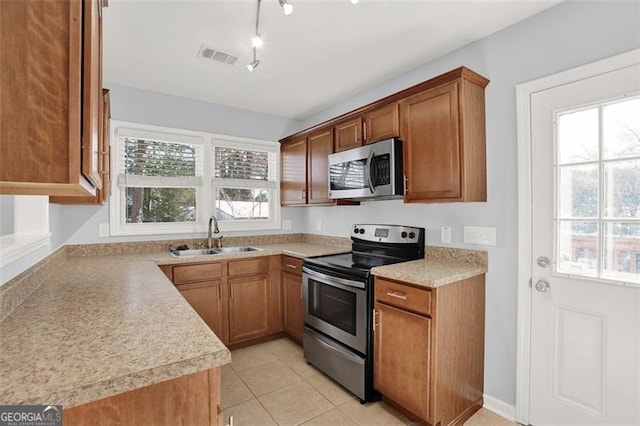 kitchen featuring sink, light tile patterned floors, appliances with stainless steel finishes, and rail lighting