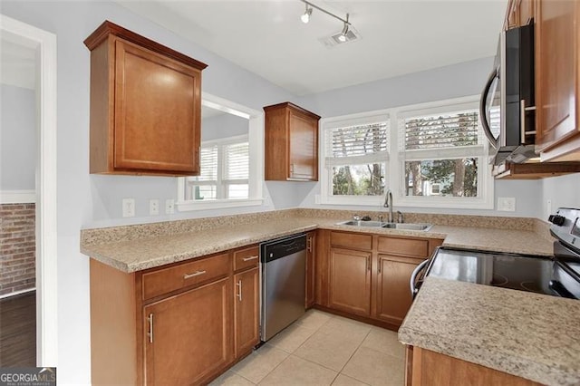 kitchen with sink, light tile patterned floors, light stone countertops, track lighting, and stainless steel appliances