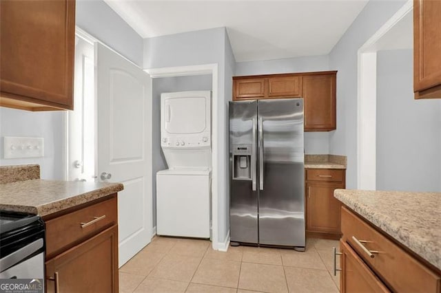 kitchen with light tile patterned floors, stainless steel appliances, and stacked washer and dryer