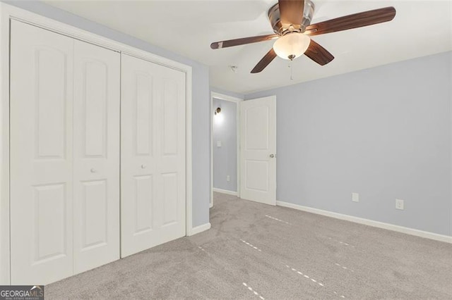 unfurnished bedroom featuring light carpet, a closet, and ceiling fan