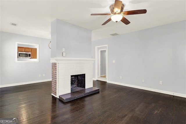 unfurnished living room featuring a fireplace, ceiling fan, and dark hardwood / wood-style flooring