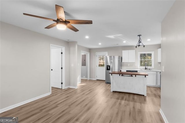 kitchen with light hardwood / wood-style floors, white cabinetry, wooden counters, stainless steel refrigerator with ice dispenser, and decorative light fixtures