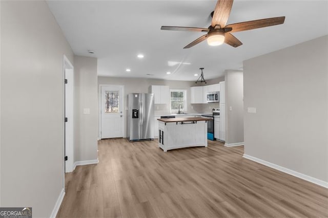 kitchen with light hardwood / wood-style flooring, ceiling fan, white cabinetry, a kitchen island, and stainless steel appliances