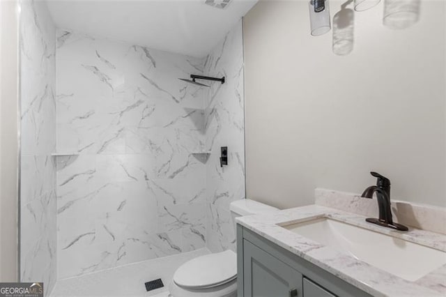 bathroom featuring vanity, toilet, and tiled shower