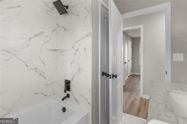 bathroom with vanity, hardwood / wood-style flooring, and tiled shower / bath