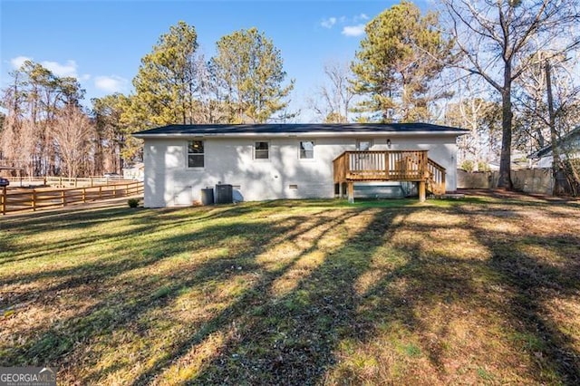 rear view of property featuring central AC, a wooden deck, and a yard