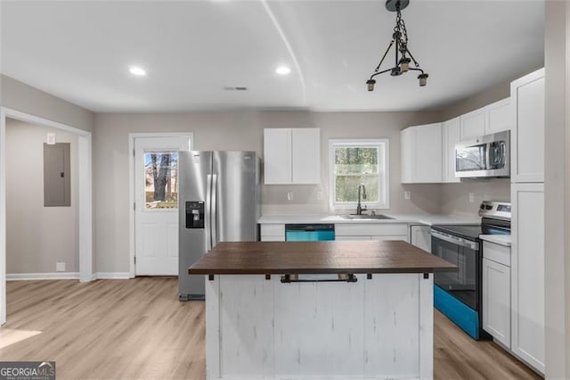 kitchen featuring a center island, white cabinetry, butcher block counters, stainless steel appliances, and sink