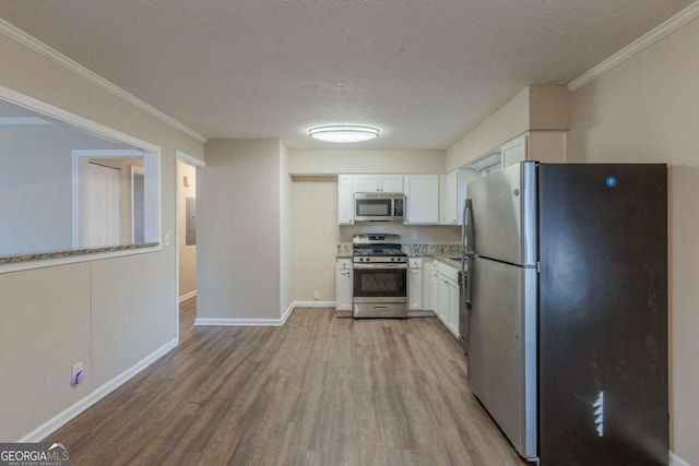 kitchen with light hardwood / wood-style floors, a textured ceiling, white cabinets, ornamental molding, and stainless steel appliances