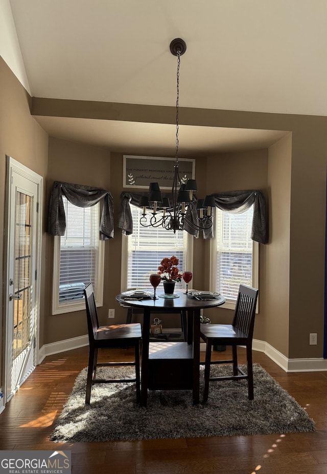 dining area featuring an inviting chandelier, lofted ceiling, and dark hardwood / wood-style floors