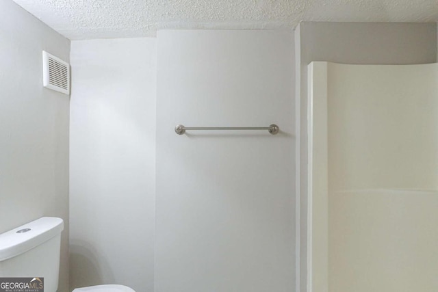 bathroom with toilet and a textured ceiling