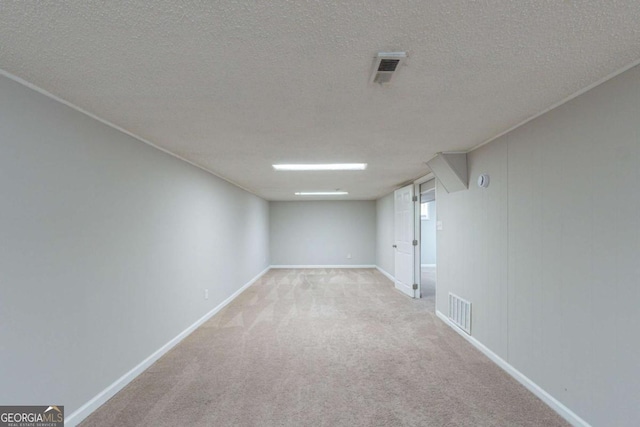 spare room featuring light colored carpet and a textured ceiling