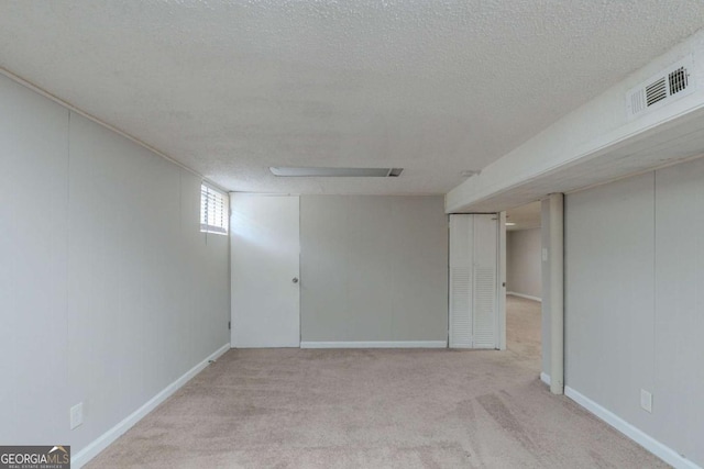 basement with light colored carpet and a textured ceiling