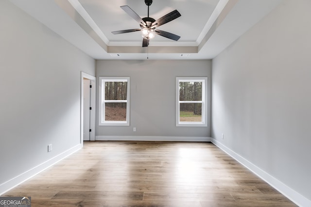 spare room with a raised ceiling, ceiling fan, ornamental molding, and light hardwood / wood-style floors