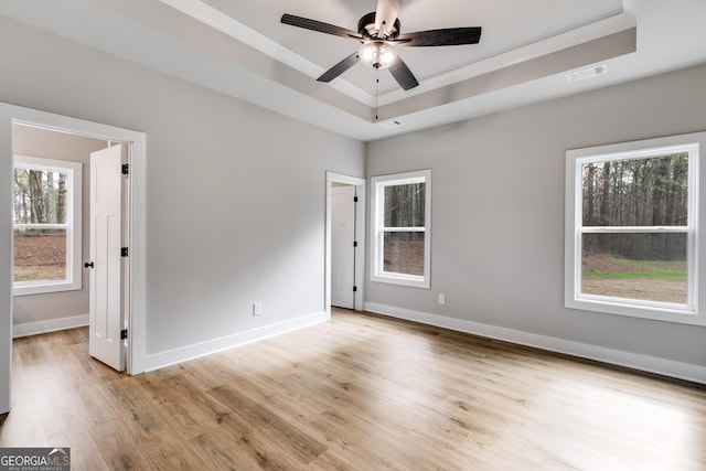 interior space featuring ceiling fan, a raised ceiling, and light hardwood / wood-style flooring