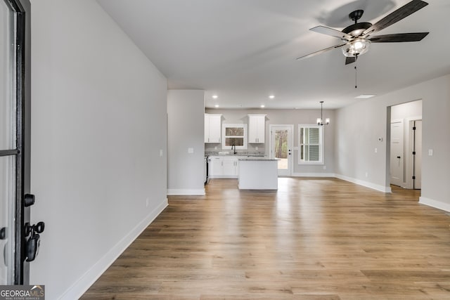 unfurnished living room with sink, ceiling fan, and light wood-type flooring