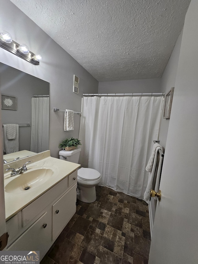 bathroom featuring visible vents, toilet, stone finish floor, vanity, and a textured ceiling