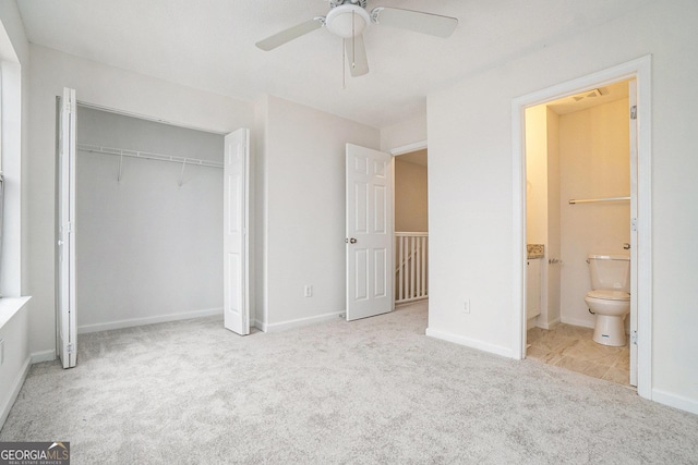 unfurnished bedroom featuring ensuite bath, light colored carpet, ceiling fan, and a closet