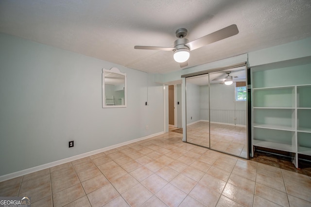 unfurnished bedroom featuring a textured ceiling, a closet, ceiling fan, and light tile patterned flooring