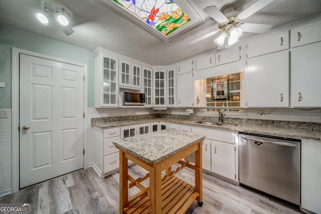 kitchen featuring sink, a textured ceiling, stainless steel appliances, light stone countertops, and white cabinets