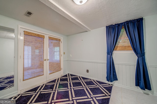 interior space with tile patterned flooring, french doors, and a textured ceiling