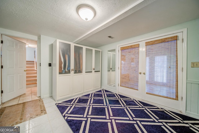 entryway with tile patterned flooring, french doors, and a textured ceiling