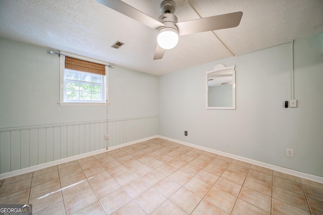 spare room featuring light tile patterned floors, a textured ceiling, and ceiling fan